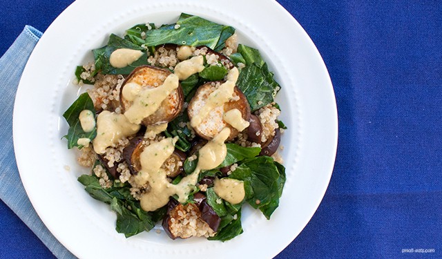 A quinoa salad with roasted eggplant and sautéed collard greens topped with a protein-packed hummus dressing.